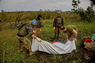 Украинские военные поднимают тело солдата ВСУ, найденное в окрестностях села Дементиевка