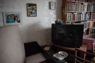 A television with bullet holes next to some family photos in the living room of the apartment where the Chechen soldiers lived