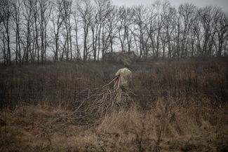 Украинский артиллерист собирает дрова, чтобы использовать их для обогрева укреплений