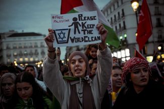 Участница пропалестинской акции протеста в Мадриде держит в руках антисемитский плакат, 21 октября 2023 года