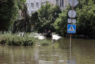 Жители Херсона плывут в лодке по одной из затопленных улиц города