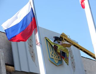 Рабочий заклеивает герб Украины на правительственном здании в Керчи, 20 марта 2014 года