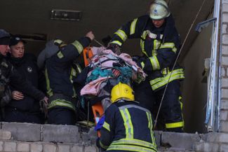 Спасатели выносят раненого из разрушенного дома в Краматорске