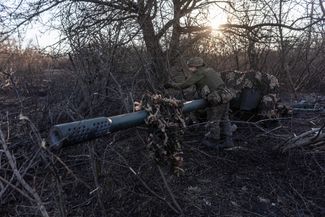 Украинский солдат натягивает камуфляжную ткань на противотанковую пушку «Рапира»