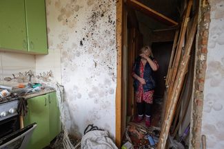 Жительница поселка Нина Брузенцева осматривает свою кухню, разрушенную при обстреле