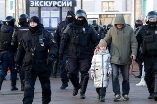 A man with a child being escorted away by riot police. According to <a href="https://ovdinfo.org/articles/2022/03/06/razbitye-golovy-i-elektroshokery-itogi-antivoennoy-akcii-6-marta?utm_source=tg&amp;utm_medium=social" rel="noopener noreferrer" target="_blank">OVD-Info</a>, at least 113 minors were arrested at anti-war protests on March 6.