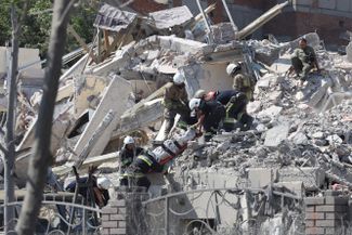 Спасатели извлекают погибшего из здания в Сергеевке, разрушенного ракетным ударом