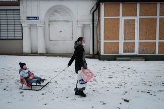 Жительница Краматорска везет на санках своего трехлетнего сына. В ее руках — гуманитарная помощь