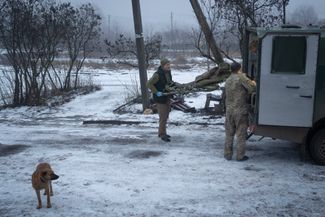 Украинские военные заносят раненого сослуживца в медпункт рядом с Бахмутом, где сейчас идут бои