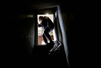 Жительница Запорожья спускается в подвал в своем доме, используемый в качестве бомбоубежища