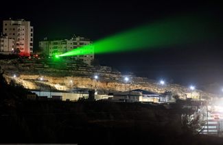 Палестинцы направляют лазерный луч на тюрьму на Западном берегу перед освобождением палестинских заключенных. 30 ноября 2023 года