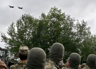 Ukrainian troops watch F-16s flying overhead at the unveiling ceremony. August 4, 2024.