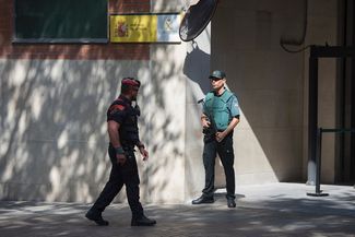 Сотрудник региональной полиции Каталонии Mossos проходит мимо сотрудника государственной полиции Guardia Civil<br>
