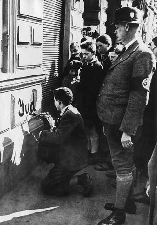 Мальчик пишет «Juden» («евреи») на стене магазина. Вена, 1938 год