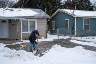 Житель техасского города Уэйко разгребает сугробы перед домом