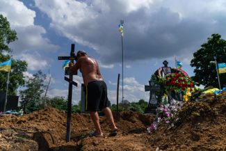Работник кладбища ставит крест на могиле военнослужащего украинской армии Сергея Марченко в Покровске Донецкой области. 26-летний Марченко служил в составе артиллерийского взвода в Донецкой области. Был убит 28 июля
