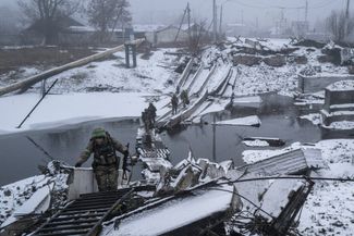 Украинские военные переправляются через речку Бахмутка в Бахмуте по импровизированному мосту из поддонов. 29 января 2023 года