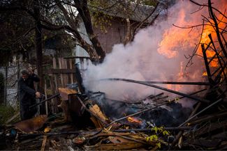 Житель Бахмута тушит пожар после обстрела города. За город, расположенный в Донецкой области, уже несколько месяцев идут бои — он находится под постоянным обстрелом