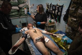 Военные врачи оказывают первую помощь раненому бойцу ВСУ