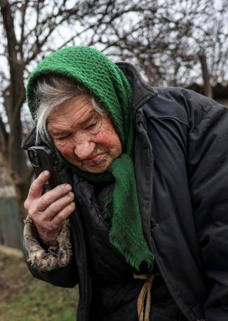 Местная жительница говорит по телефону с родственниками во время эвакуации