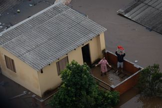 Жители Каноаса рядом со своим затопленным домом в ожидании эвакуации на вертолете экстренных служб, 4 мая