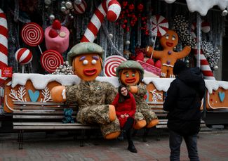 Киевлянка позирует для фотографии с людьми, одетыми в костюмы рождественских имбирных пряников в форме ВСУ
