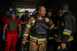 Firefighters hid during an air raid while working at the site of the Russian raid in Zaporozhye. Ukraine's State Emergency Service says Russian forces often attack rescuers when they are extinguishing fires. 