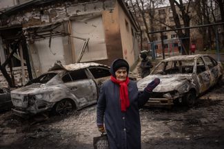Местная жительница рядом с машинами, пострадавшими от российского обстрела 1 декабря. 