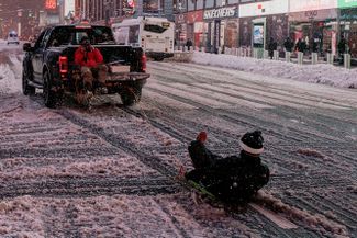 Мужчина катится на санках, привязанных к машине, по площади Таймс-сквер, 1 февраля 2021 года