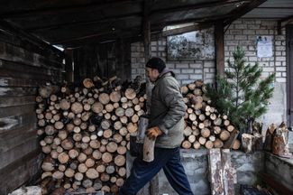 Житель Лимана носит дрова, с помощью которых он отапливает свой дом