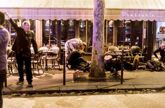 Люди лежат на веранде перед парижским кафе «Бон Бьер», на которое была совершена террористическая атака. 13 ноября 2015 года