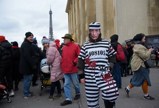 Участник акции в Париже в окровавленном костюме заключенного и маске с лицом президента РФ Владимира Путина