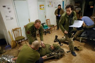 Армейские врачи оказывают первую помощь раненному военнослужащему ВСУ перед отправкой в госпиталь. 