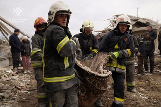 Спасатели несут тело погибшего после ракетного удара в Львовской области, 9 марта 2023 года