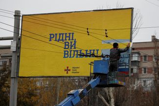 Муниципальный работник размещает на билборде плакат с надписью «Родные, вы свободны!» поверх пророссийского постера, установленного во время оккупации Херсона. Город был освобожден 11 ноября