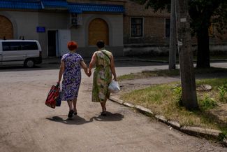 Женщины идут по улице после получения гуманитарной помощи