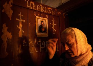 Женщина во время службы в подвале универмага возле сгоревшего Свято-Митрофановского храма в Лисичанске