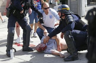 Полицейские и мужчина, пострадавший в ходе столкновений перед матчем в Марселе. 11 июня 2016 года.