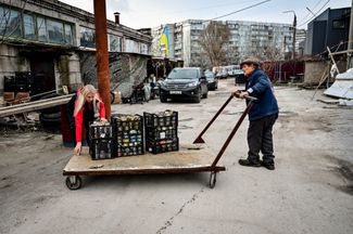Волонтеры Дядя Федор и Валентина Тышкевич везут на тележке коробки с готовыми окопными свечами