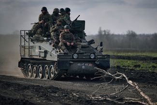Украинские военные едут на бронетранспортере в районе передовой в Бахмуте