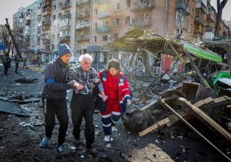 Киевляне помогают раненому жителю разрушенного дома