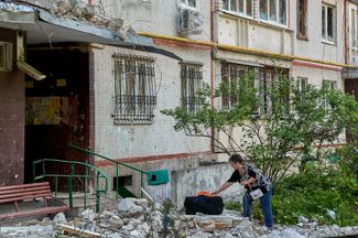 Женщина возле дома в Северной Салтовке, частично разрушенного при обстреле. 23 мая 2022 года