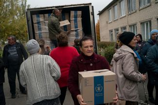 Люди получают коробки с гуманитарной помощью в Михайло-Лукашево