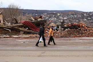 Жители Купянска идут мимо завалов с пакетами гуманитарной помощи. Рядом с городом Харьковской области сейчас идет российское наступление