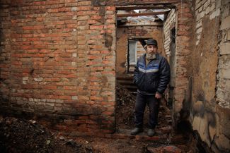 Roman Chubach stands inside the remains of his destroyed home in Lebyazhe
