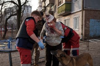 Работники скорой помощи помогают киевлянке, раненной во время обстрела