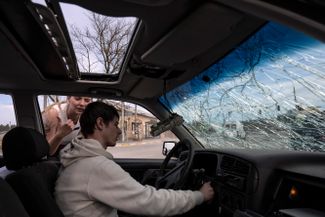 Житель Ирпени (Киевская область) пытается завести свою машину, почти уничтоженную во время российской атаки на город.