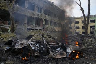 Обгорелый остов машины во дворе мариупольского роддома после бомбардировки. 9 марта 2022 года