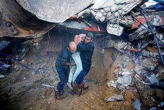 Спасатели достают тело подростка из-под завалов дома в городе Дейр-эль-Балах в центральной части сектора Газа, 15 октября 2023 года