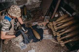 Военнослужащий 35-й бригады ВСУ Андрей подготавливает минометные снаряды на огневой позиции около освобожденного села